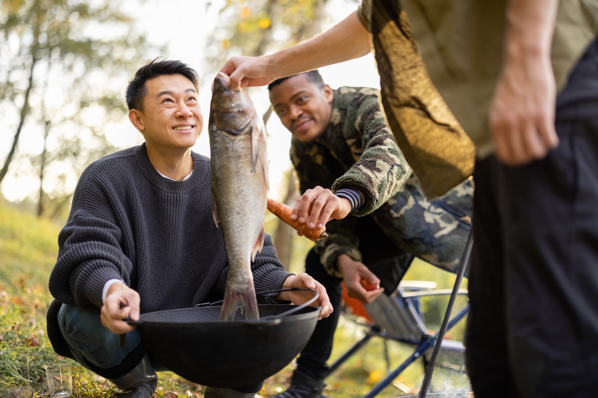 Man put big fish in cauldron for cooking Ukha soup